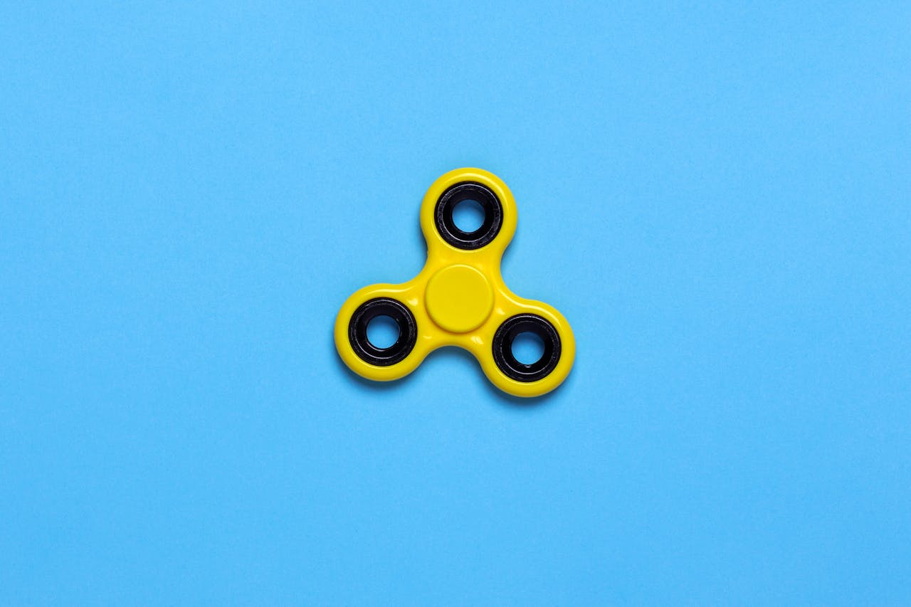 Yellow Tri-spinner Fidget Toy on Blue Tabletop